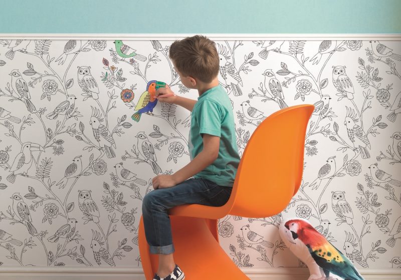 Мальчик раскрашивает бумажные обои на стене детской комнаты