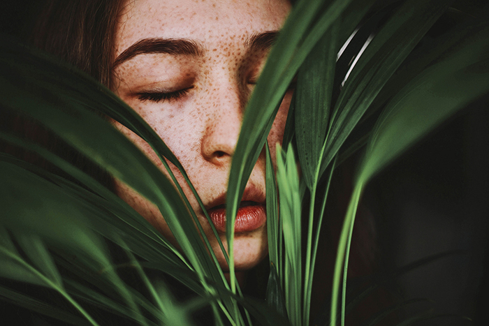 A girl posing indoors covered by plants
