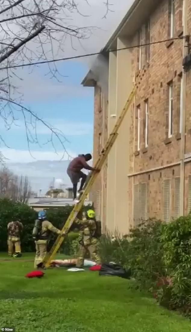 Video from the scene shows one man hanging out his window who had to be rescued by fire crews using a large ladder (pictured)
