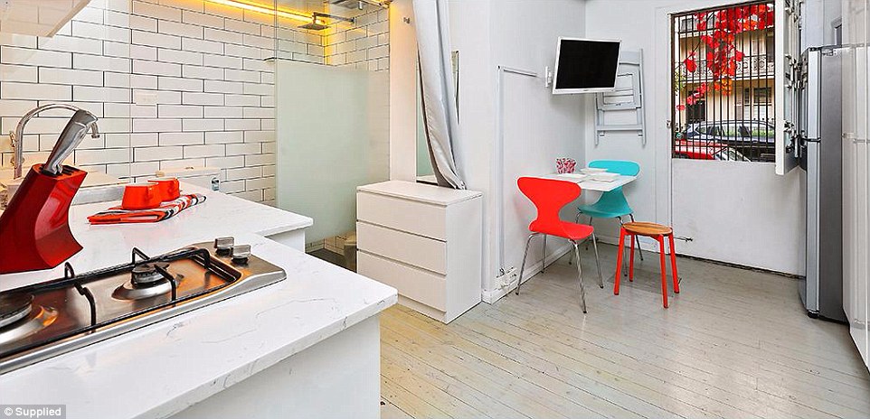 The kitchen sits adjacent to the bathroom and the living area itself is cramped with a television mounted on the wall