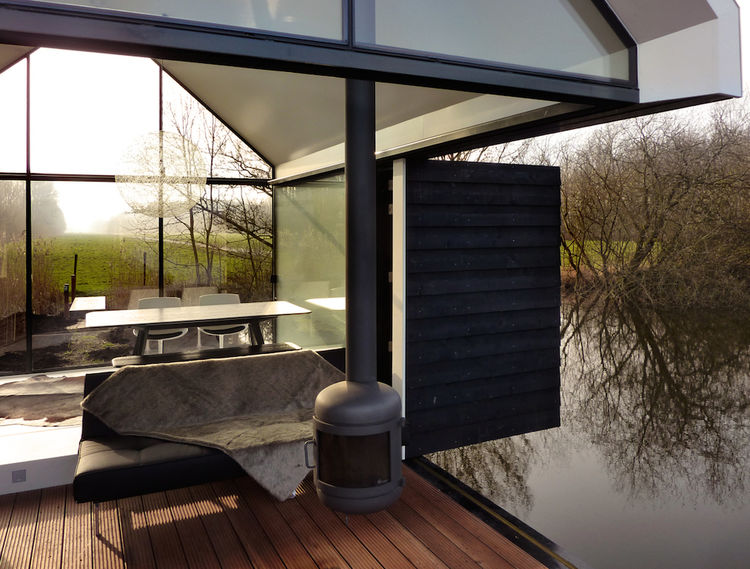 Терраса маленького стеклянного домика у озера в Голландии