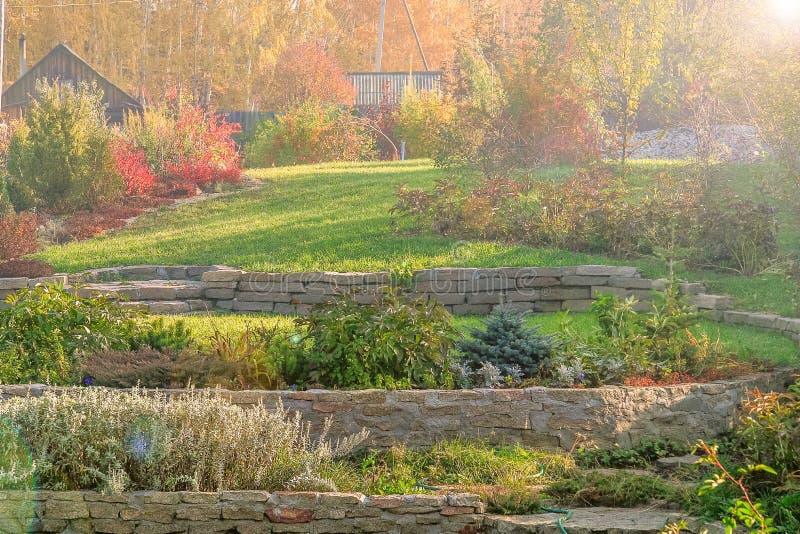 Autumn garden with lawns, retaining walls, alpine slide, sun glare stock photo