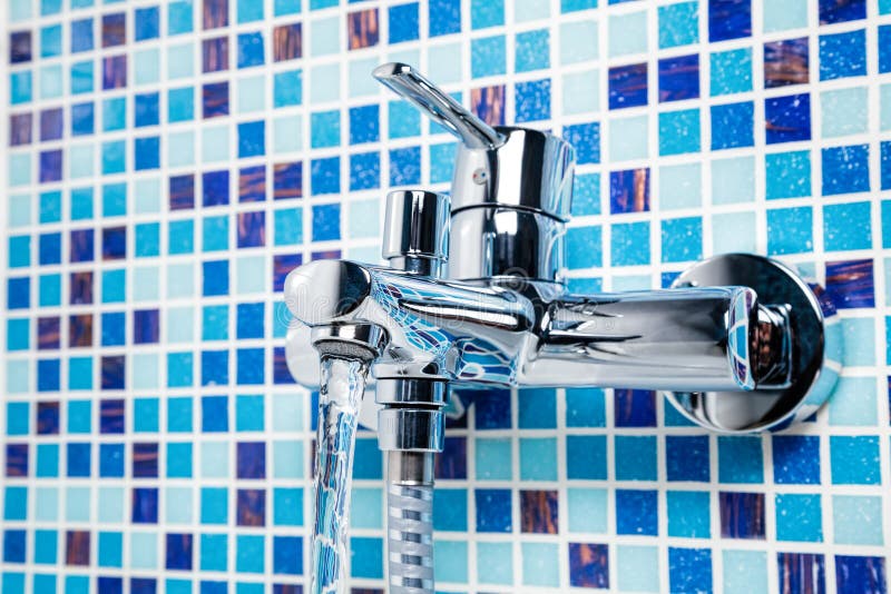Bathtub tap on a blue tiled wall stock images