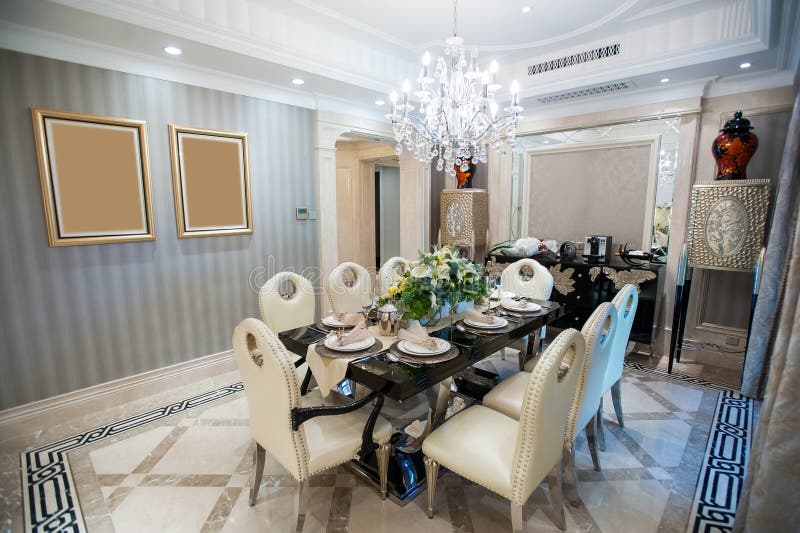 Beautiful dining room with Chandelier in a mansion. Marble decorated.black marble table and white leather chairs royalty free stock image