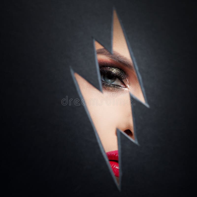 Beautiful female eye with color makeup. Cutout in paper in the form of a lightning. Free space royalty free stock images