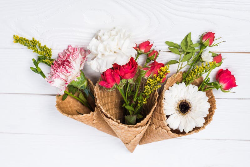 Beautiful floral composition with flowers and waffle cones on white wooden background royalty free stock photo Beautiful floral composition with flowers and waffle cones on white wooden background royalty free stock photo