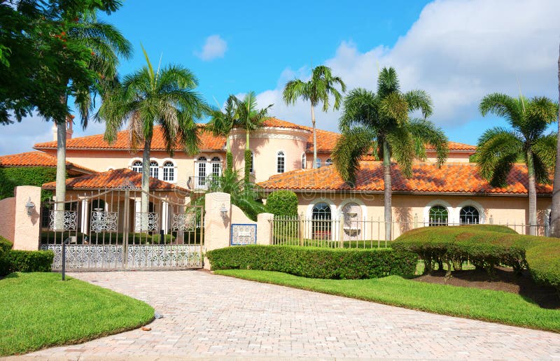 Beautiful Spanish style luxury mansion residential home with a privacy gate and palm trees. On a blue sky sunny morning stock photo