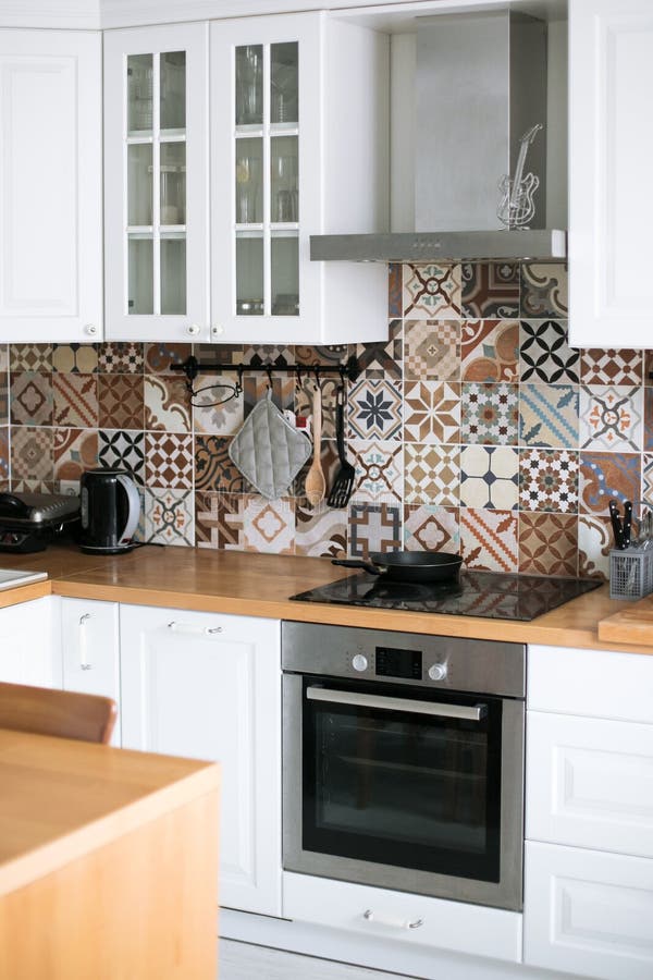 Beautiful stylish white real kitchen in Scandinavian style with wooden top and Spanish tiles. Vertical royalty free stock images