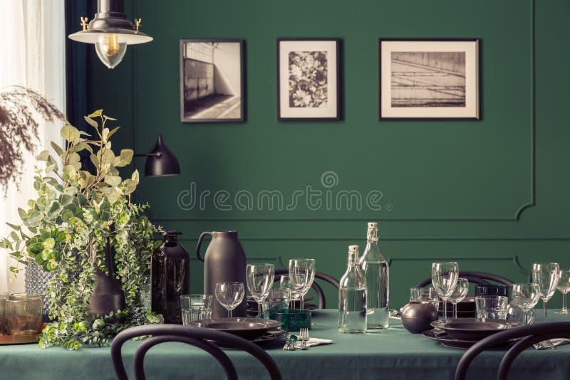 Black and green design of elegant dining table in fashionable interior with gallery of posters on the wall. Concept royalty free stock image