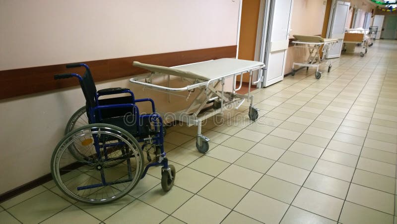 Bright, clean hallway in a medical facility - along the walls are medical bed and wheel-chair royalty free stock photography