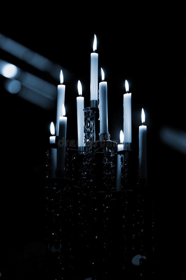 Candle Chandelier. Monotone chandelier with lit candles on a dark background stock photo