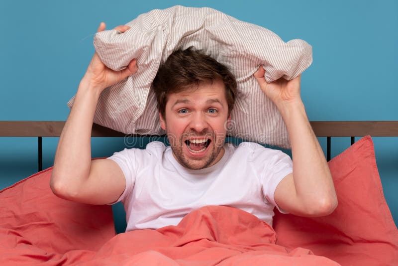 Caucasian man throwing pillow in the bed stock images