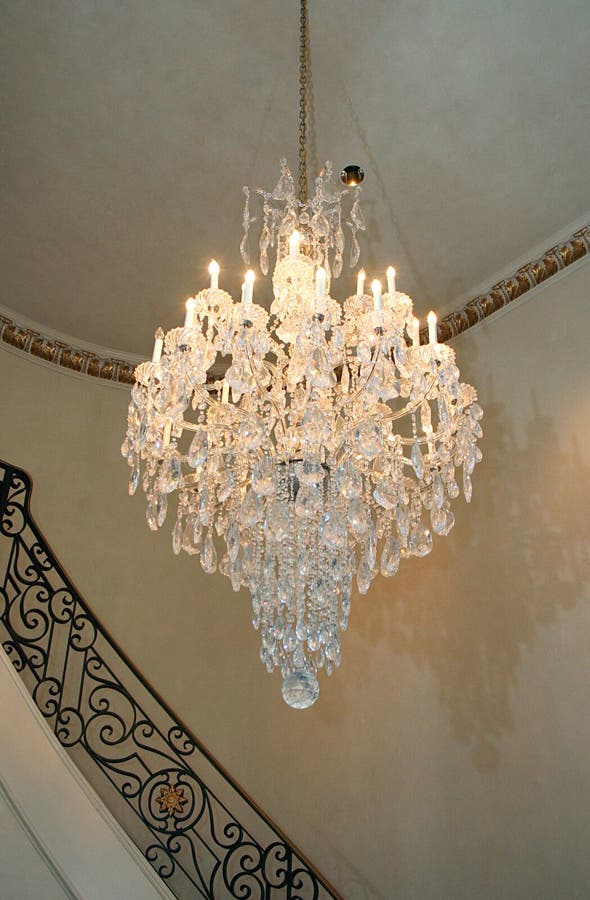 Chandelier. A beautiful crystal chandelier hangs in the entryway of a home stock image