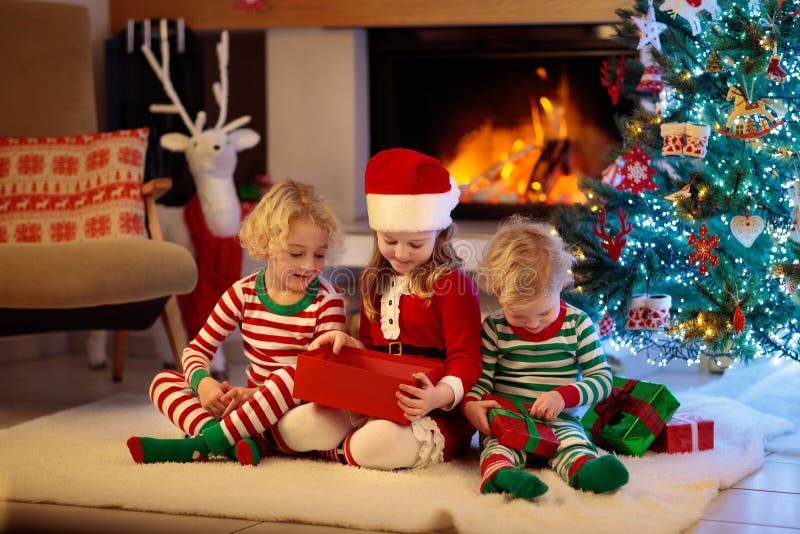 Child at Christmas tree. Kids at fireplace on Xmas. Children at Christmas tree and fireplace on Xmas eve. Family with kids celebrating Christmas at home. Boy and royalty free stock photography