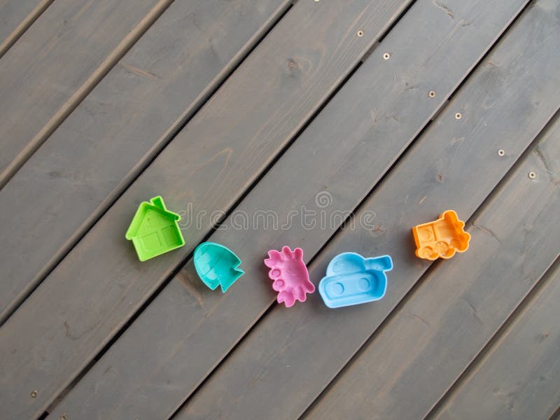 Children`s plastic toys of different colours on the wooden floor on the terrace of a country house. Horizontal orientation, space. For text stock image