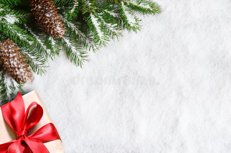 Christmas background, green pine branches, cones and gift box on snow background. Creative composition with border and copy space stock image Christmas background, green pine branches, cones and gift box on snow background. Creative composition with border and copy space stock image