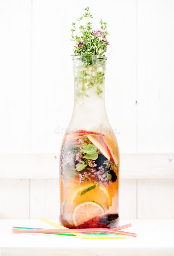 Cold Infused Detox Water Summer lemonade with berries, herbs and fruits in a glass bottle. On a white wooden background royalty free stock image
