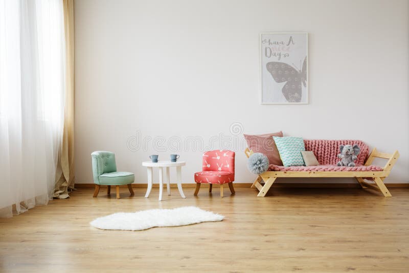 Colorful children`s chairs. And white table in bright room with mint pillow on sofa royalty free stock photography