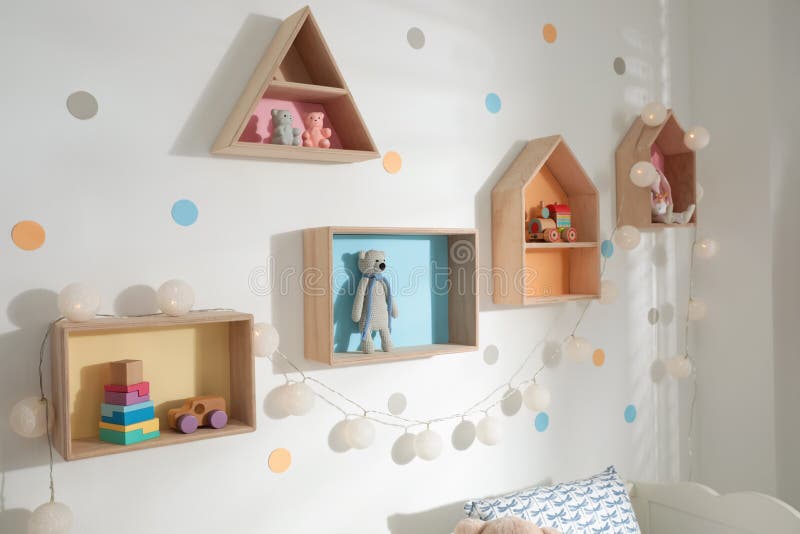 Colorful house shaped shelves on white wall. Children`s room interior design. Colorful house shaped shelves on white wall indoors. Children`s room interior stock photography