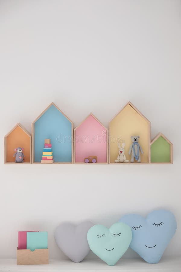 Colorful house shaped shelves on white wall and soft pillows. Children`s room interior design. Colorful house shaped shelves on white wall and soft pillows royalty free stock photos
