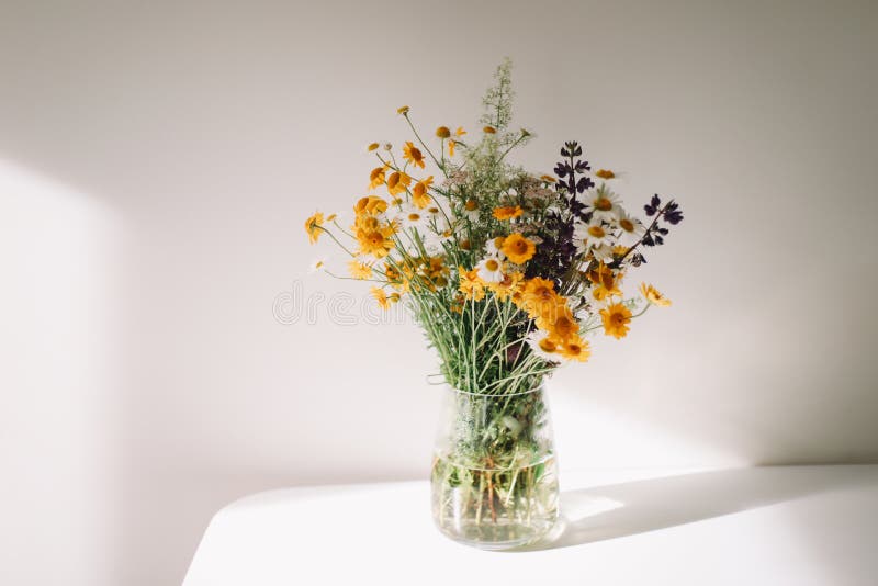 Colorful midsummer bunch of wildflowers. Bouquet of wild natural flowers in a vase on the table, selective focus. Bouquet of wild natural flowers in a vase at royalty free stock image