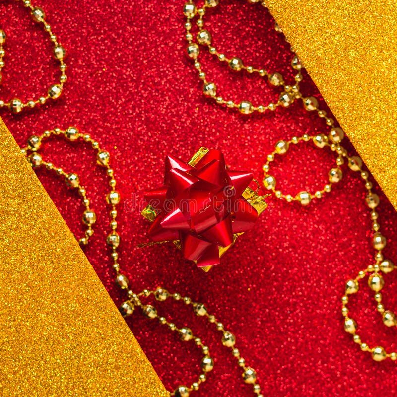 Combination of red and gold with a gift box, beautiful beads, a shiny holiday background. Christmas card, background for congratulations. A combination of red stock photo