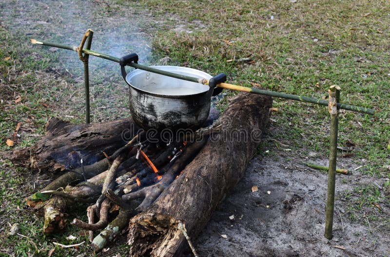 Cooking rice using pot in outdoor nature. Food Camping cooking over a fire using dry firewood and use stone as stove stand. stock image