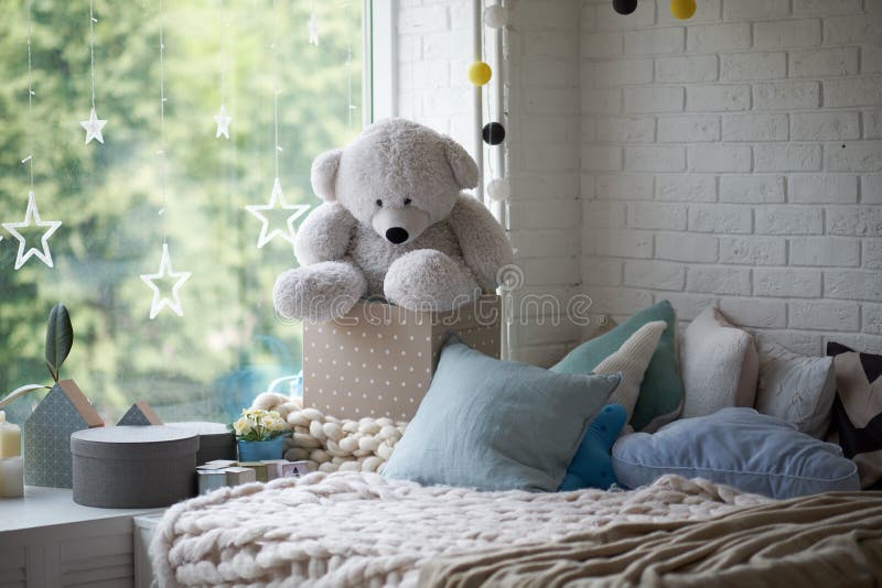 Cozy children`s room in bright soft colors, pillows and a blanket are lying on the bed stock image