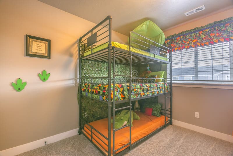 Cozy room interior with a colorful triple bunk bed for children. Bright sunlight streams inside the bedroom through the glass window with blinds and multi royalty free stock photos