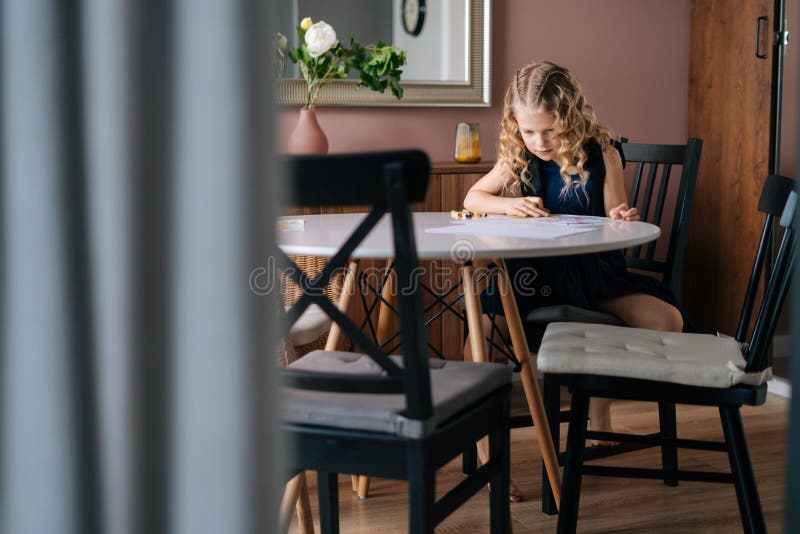 Creative kid girl doing homework at the table in cozy children`s room. Concept of child creative activity stock photos