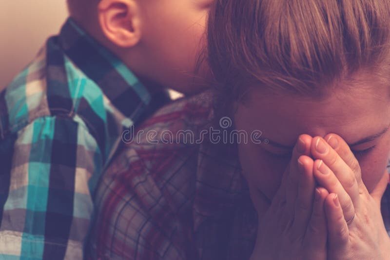 Crying unhappy mother with child at home. Crying unhappy women covering her face with hands while little child standing next to her. Tired and depressed mother stock photos