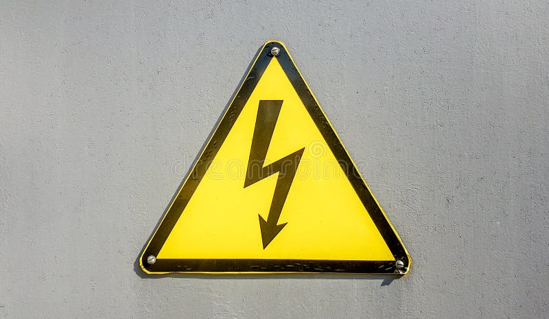 Danger sign of high voltage electricity. Yellow triangular sign with a lightning in the center. This warning is written on an old stock photography