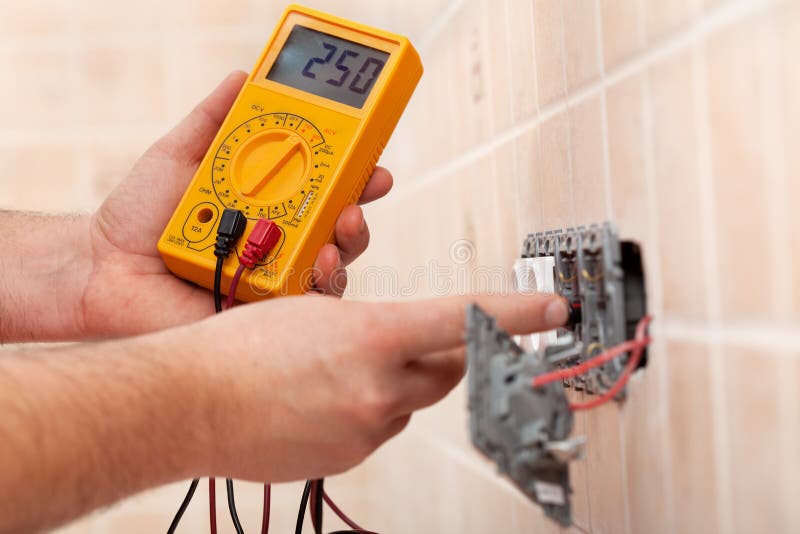 Electrician hands checking voltage in a partially mounted electrical socket - closeup royalty free stock photo