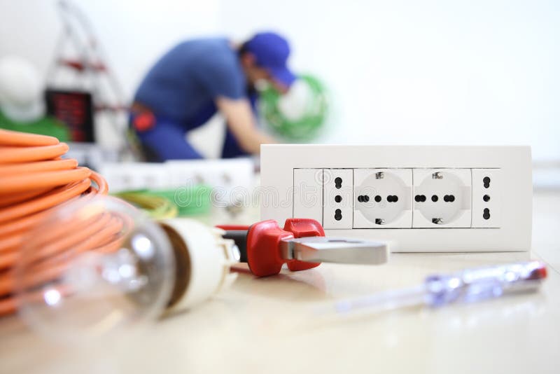 Electrician work with electrical equipment in the foreground  bulb, tools and socket, electric circuits, electrical wiring stock images