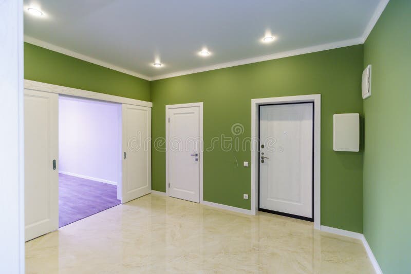 Empty hallway with green walls and marble floor in a new apartment with a fresh renovation. Doors lead from the hall to different rooms stock photos