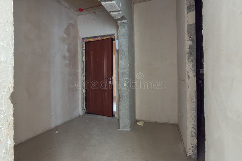 The entrance to apartment is a new building, the front door and bare concrete and plastered walls. The entrance to the apartment is a new building, the front royalty free stock image