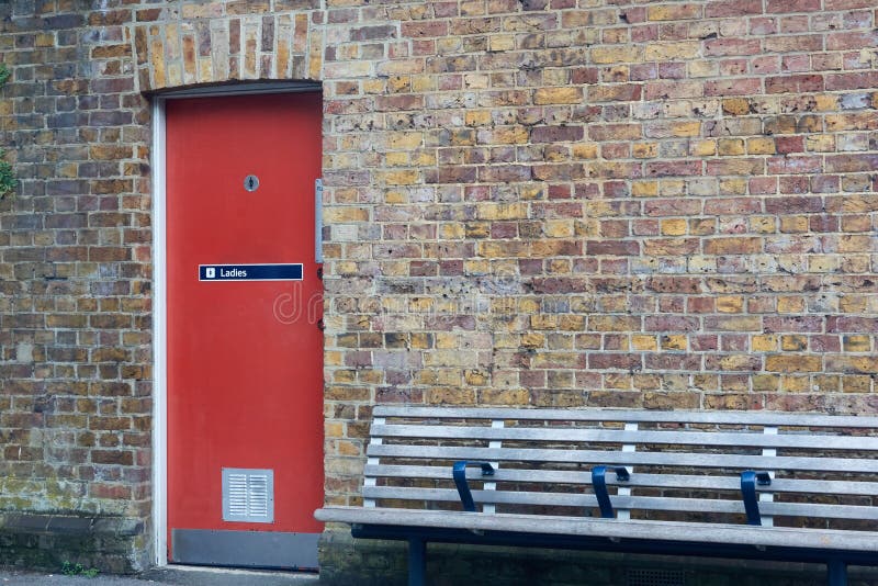Entrance to the women`s toilet. Red door in a brick wall stock photography Entrance to the women`s toilet. Red door in a brick wall stock photography