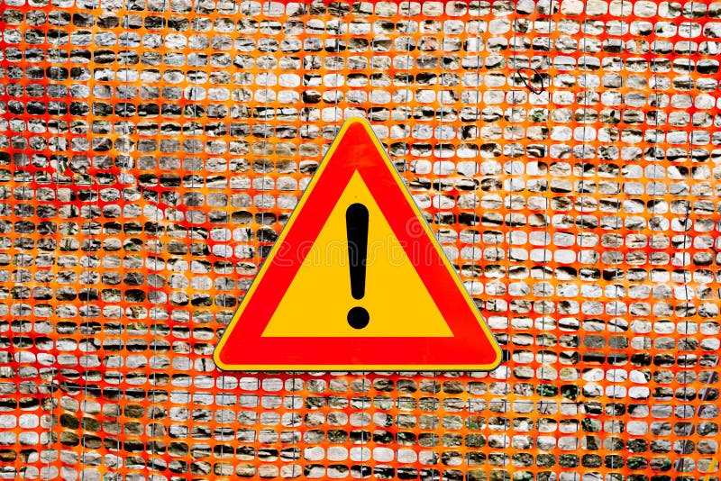 An exclamation point on a yellow background, in a red triangular sign. The texture of the yellow plastic mesh fence on stock images