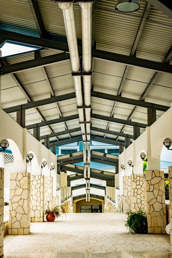 Exterior hallway corridor with high ceiling, lights and fixtures above and along stone wall columns royalty free stock images