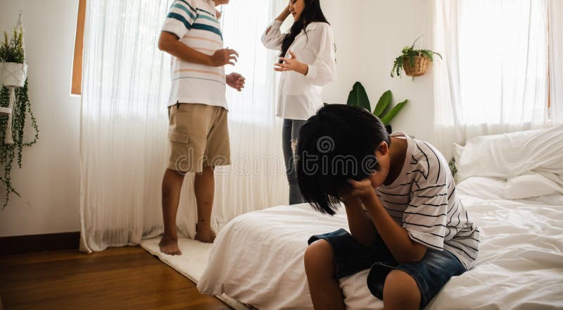 Family conflict and problem between father and mother arguing in bed room while Asian sad & upset child or son crying on bed. Unhappy and trouble couple or royalty free stock photography