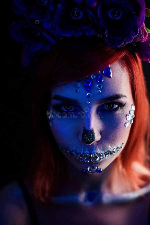 Fashion model with halloween skull makeup with glitter and rhinestones with creative color lightning. Fashion model with halloween skull makeup with glitter and stock photo