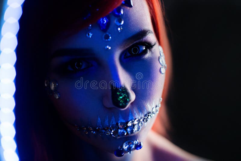 Fashion model with halloween skull makeup with glitter and rhinestones with creative color lightning. Fashion model with halloween skull makeup with glitter and stock images
