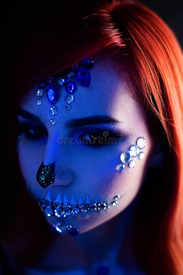 Fashion model with halloween skull makeup with glitter and rhinestones with creative color lightning. Fashion model with halloween skull makeup with glitter and royalty free stock photos