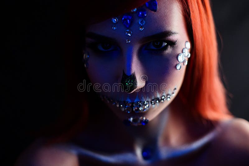 Fashion model with halloween skull makeup with glitter and rhinestones with creative color lightning. Fashion model with halloween skull makeup with glitter and stock photos