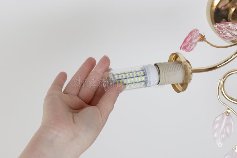 Female hand inserts a light bulb into the threaded socket. Installation of household LED lamps of corn type, in the lamp holder,. There is a toning stock photography