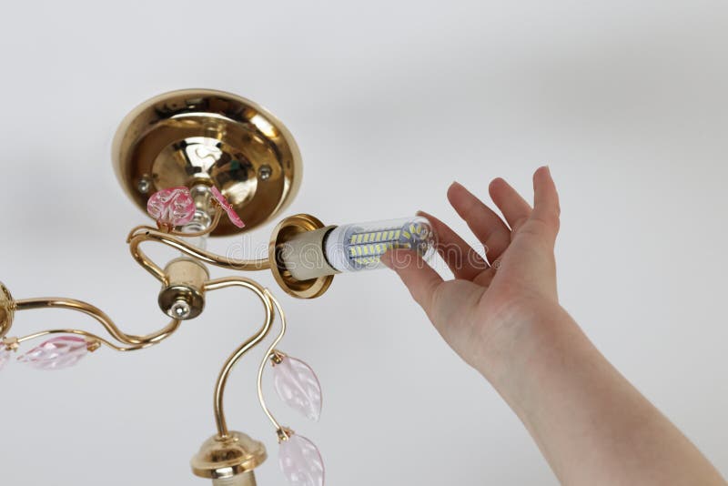 Female hand inserts a light bulb into the threaded socket. Installation of household LED lamps of corn type, in the lamp holder,. There is a toning stock image