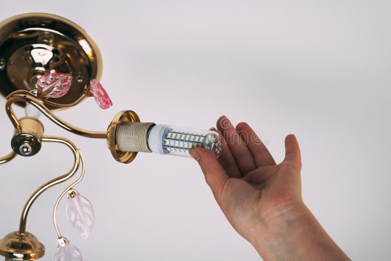 Female hand inserts a light bulb into the threaded socket. Installation of household LED lamps of corn type, in the lamp holder,. There is a toning royalty free stock photos