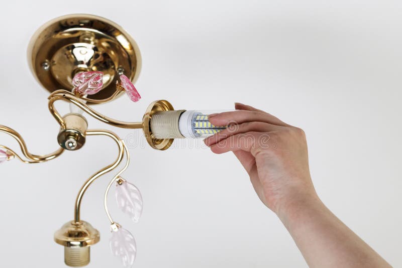 Female hand inserts a light bulb into the threaded socket. Installation of household LED lamps of corn type, in the lamp holder,. There is a toning royalty free stock photography