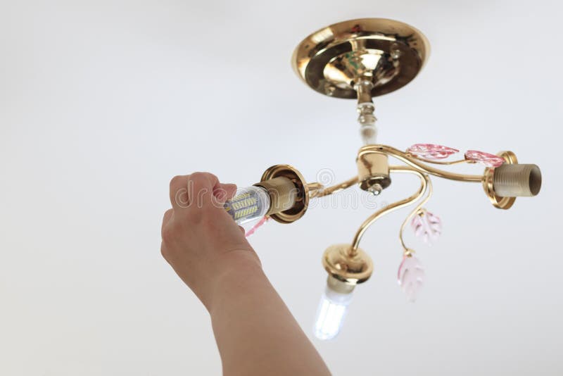 Female hand inserts a light bulb into the threaded socket. she is shining. Installation of household LED lamps of corn type, in. The lamp holder, there is a royalty free stock image