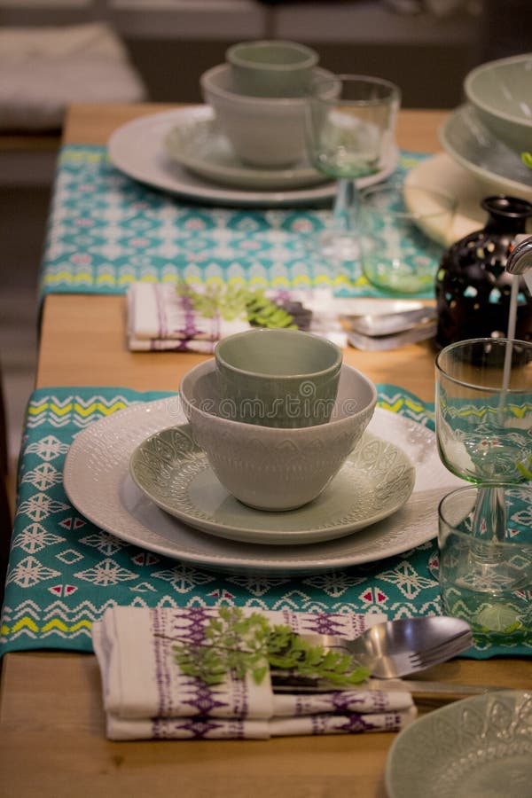 Festive table setting in white and green tones. Plates wine glasses on ethnic napkin with ornament stock image